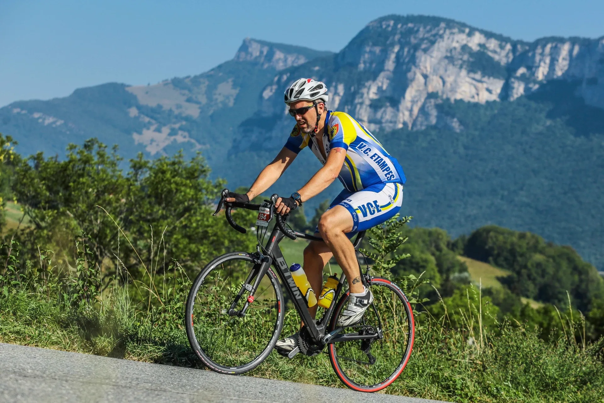 Rennradfahrer auf Bergstraße mit Alpenpanorama – Winsole Carbon-Einlegesohle für maximale Kraftübertragung